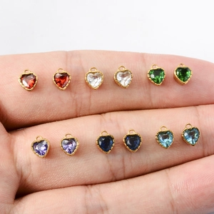 Colorful heart zircon pendants with 18k gold-plated frames on hand for scale