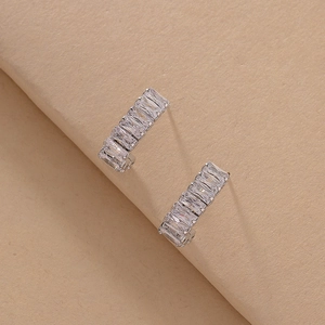 Close-up of silver geometric hoop earrings featuring baguette-cut zircon stones