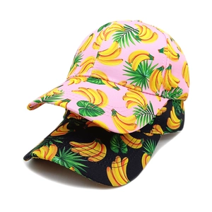 Detailed view of banana and tropical leaf prints on pink and black baseball caps