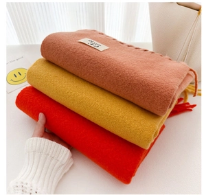 Close-up of soft solid color scarves in pink, yellow and red with fringe detail