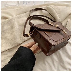 Détail du sac bandoulière marron vintage en cuir avec coutures et fermoir doré