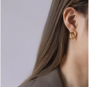 Détail de boucles d'oreilles géométriques irrégulières plaquées or 18 carats sur un mannequin
