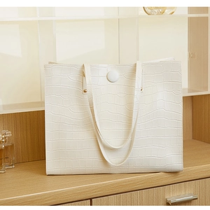 Detailed close-up showing the elegant white crocodile pattern texture on a tote bag