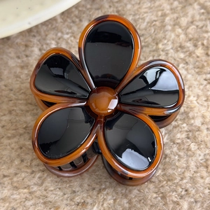 Detail of vintage amber flower hair claw clip on beige knitted fabric background
