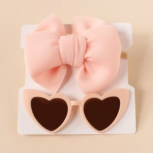Flat lay of soft pink bow nylon headband and heart-shaped sunglasses for baby girls