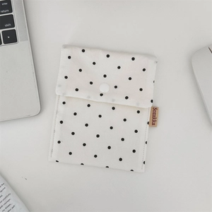 Detailed macro shot of the polka dot canvas bag's snap button closure and side woven label