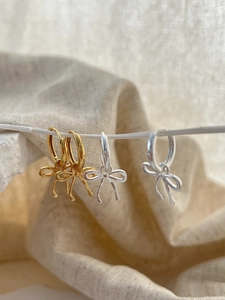 Detailed view of 925 sterling silver bow pendant earrings in gold and silver finishes
