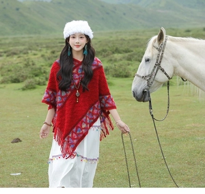 Ethnic red knitted poncho with geometric patterns and fringe hem details on a model