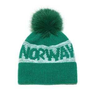 Green knit beanie with NORWAY lettering and large faux fur pom-pom for winter skiing