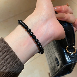 Close-up of polished black obsidian beaded bracelet on wrist with luxury background