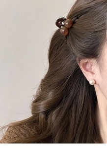 Vue détaillée d'une pince à cheveux en résine ambrée et boucles d'oreilles en perles