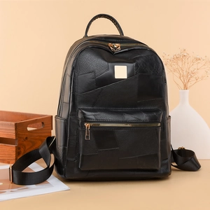 Detail of black leather patchwork backpack featuring gold zippers and reinforced handles