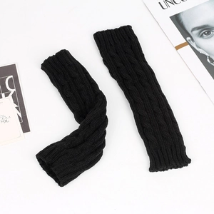 Detail shot of black cable-knit arm warmers on a minimalist background with magazines