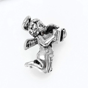 Macro shot of silver vintage angel brooch with intricate carved details and polished finish