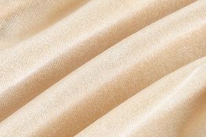 Gros plan sur le tissu de robe doré champagne avec texture métallique et drapé élégant