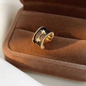 Macro d'une boucle d'oreille étoile dorée avec émail noir et pierres en zircone