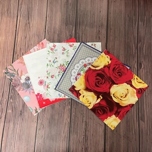 Floral printed paper napkins with assorted rose and polka dot patterns on wood background