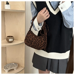 Détail du sac croissant à imprimé léopard avec pompons décoratifs et anse tressée