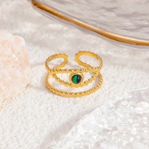 Macro view of gold-plated stainless steel ring featuring beaded texture and green gemstone