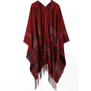 Close-up of dark red hooded knit shawl featuring vibrant plaid hem and tassel fringe detail