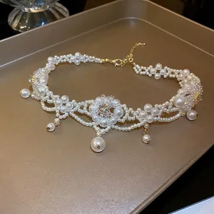 Elegant floral choker with faux pearls and sparkling crystals on a golden tray