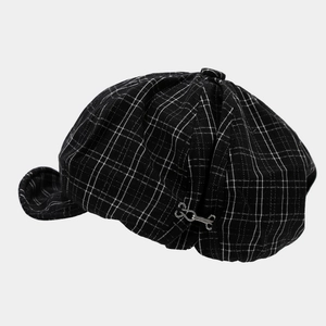 Detail view of black and white plaid newsboy hat with stylish metal chain buckle accent