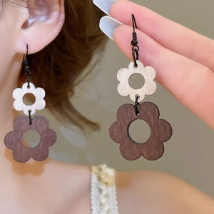 Détail de boucles d'oreilles fleurs superposées en bois sur le modèle