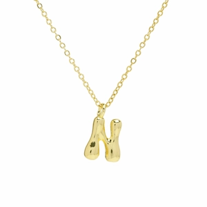 Close-up of golden balloon letter N pendant with high-shine polished fluid metal surface