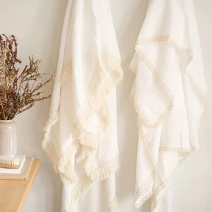 Detail of white muslin cotton baby blanket featuring delicate lace and fringe edges