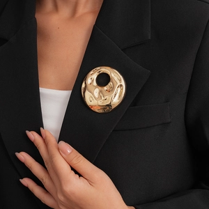 Vintage gold hollow round brooch with irregular pleated texture on black blazer lapel