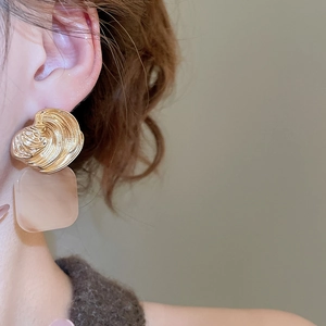 Detailed view of square resin drop earring with spiral gold metal top on a model