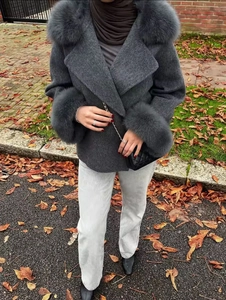 Gros plan sur un manteau en laine gris foncé avec bordure en fausse fourrure épaisse
