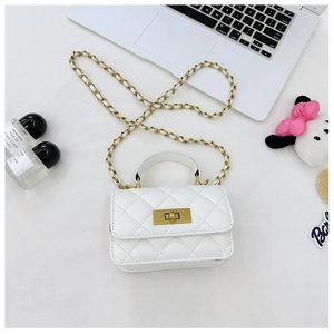 Detailed view of a white quilted mini crossbody bag with gold chain and handle in a chic setting