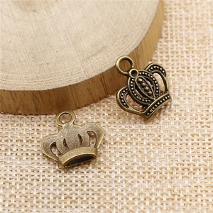 Macro detail of antique bronze crown charms on a rustic wood and fabric background