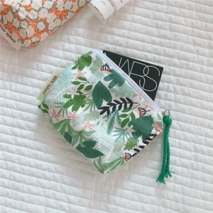 Close-up of mini cotton pouch with green leaf pattern and white zipper pull detail