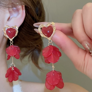 Close-up of elegant red heart petal tassel earrings worn with a chic French palace style