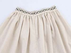 Détail de la taille d'une jupe en lin avec dentelle géométrique et plis élégants
