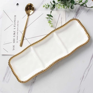 Detailed view of 3-compartment white ceramic dish with gold beaded edge on marble