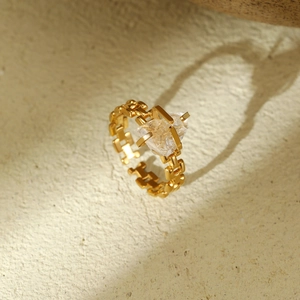 Macro shot of gold stainless steel ring with chain band and geometric gemstone