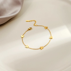 Detail shot of a minimalist gold butterfly bracelet on an elegant cream tray