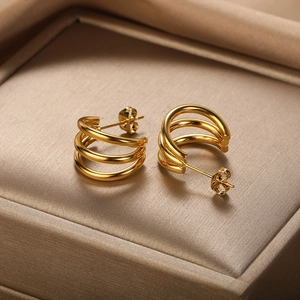 Detail of three-layer gold C-shape earrings displayed on champagne satin fabric