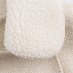 Macro detail of creamy sherpa fleece and beige suede stitching on a winter coat