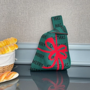 Détail du tricot d'un sac de Noël vert avec un nœud rouge et texte Merry Christmas