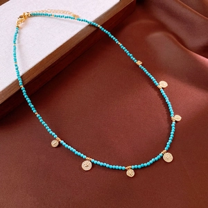 Detail of vintage turquoise beaded necklace with golden embossed coin pendants and lobster clasp