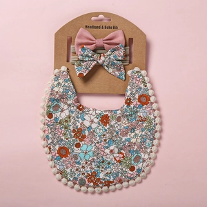 Détail du bavoir bébé bohème à fleurs avec pompons et bandeaux nœuds assortis