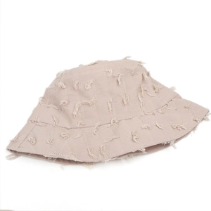 Détail du chapeau bob beige avec des patchs de fleurs et des bords effilochés usés