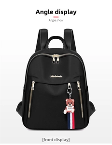 Close-up of black nylon backpack featuring gold zippers and a cute teddy bear pendant