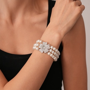 Detail of a multi-layer pearl bracelet with a sparkling diamond-encrusted flower clasp