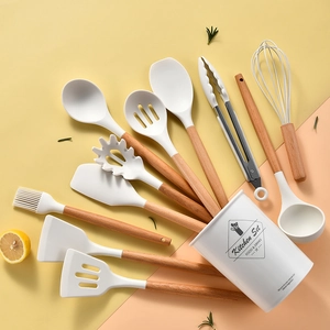 Vista piatta di utensili da cucina in silicone crema con manici in legno e secchiello