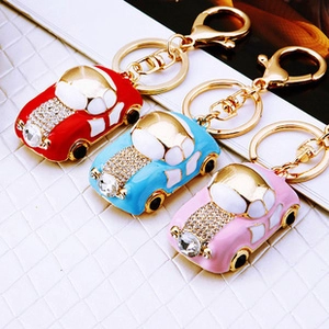 Close-up of three metal beetle keychains with rhinestones in red, blue, and pink